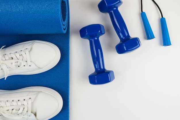 스포츠 액세서리의 개념 흰색 운동화 파란색 아령과 파란색 운동 매트 및 기타 스포츠 장비 사진
