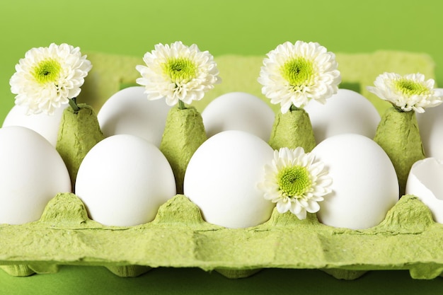 Concept of spring eggs with flowers on green background