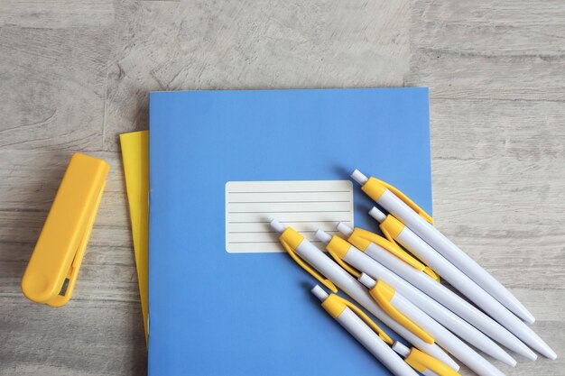 The concept of starting classes in schools Yellow pens on blue school notebooks yellow stapler next to it gray background top view space for text