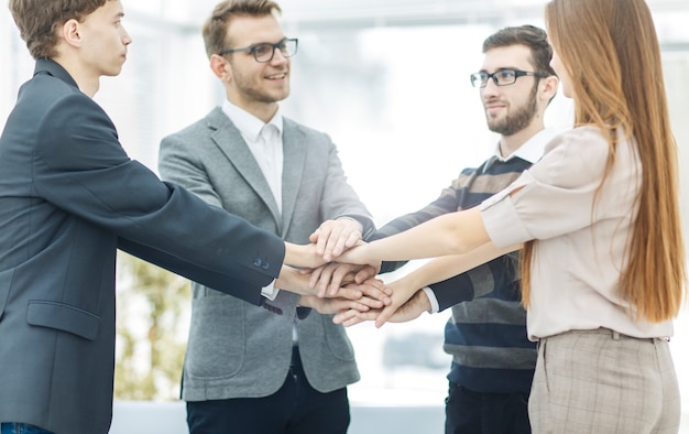 Concept of success in business friendly business team standing in a circle and joining his hands tog...