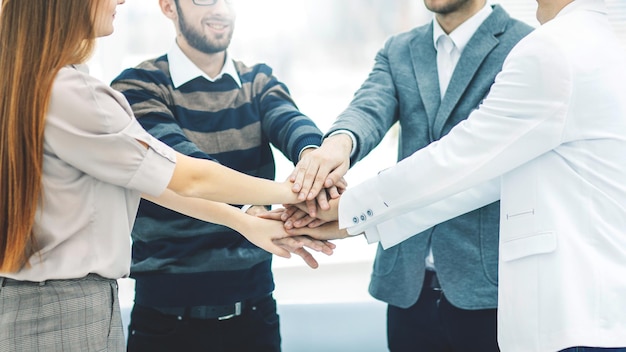 Concept of success in business friendly business team standing in a circle and joining his hands tog...