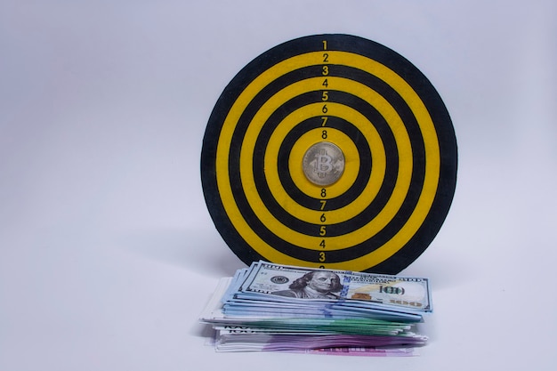 Photo concept of success and goal achievement. round dart board with a bundle of dollars, euros and a bitcoin coin in the center of the circle.