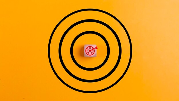 Concept of success target with a target icon on a wooden block on a yellow backgroundthe concept of achieving or targeting business goals