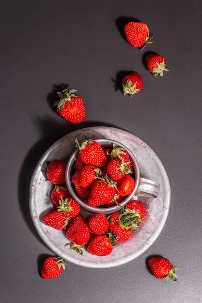 Concept of summer food with a strawberry on a black stone background. Ripe aromatic berries, modern hard light, dark shadow, top view