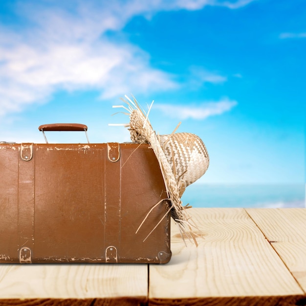 古いスーツケースとアクセサリーを持って夏の旅行のコンセプト。背景のぼやけたビーチ