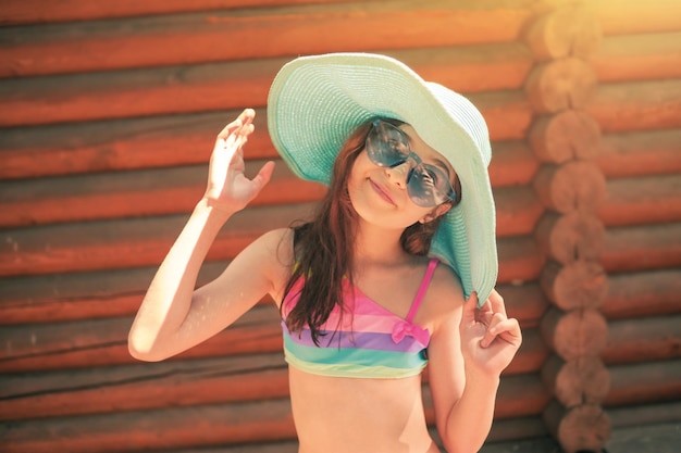 Концепция летних каникул Портрет девочки-подростка в радужном купальнике и синей шляпе