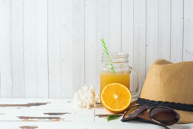 Concetto vacanze estive. cappello di paglia con succo d'arancia e conchiglie. copia spazio