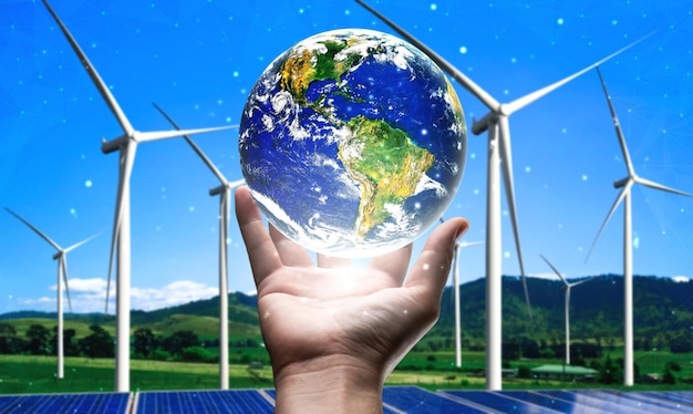 Photo concept of sustainability development by alternative energy. man hand take care of planet earth with environmentally friendly wind turbine farm and green renewable energy in background.