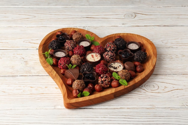 Concept of sweets with chocolate candies on white wooden background