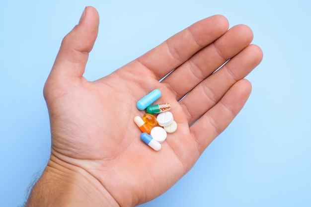 Concept of taking pills. Man`s hand holding different pills capsules