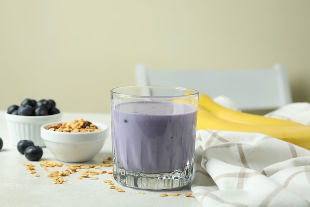 Concept of tasty breakfast with blueberry smoothie on white textured table