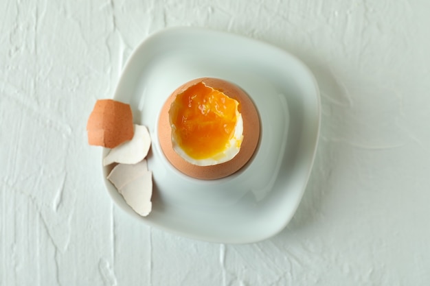 Concept of tasty breakfast with boiled egg on white textured table