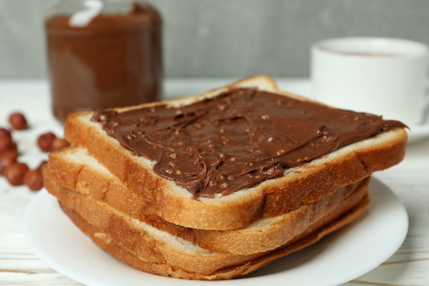 Concept of tasty breakfast with chocolate paste on white wooden table