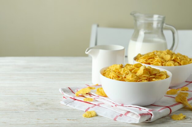 Concept of tasty breakfast with cornflakes on white wooden table