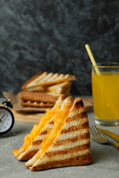 Concept of tasty breakfast with grilled sandwich on gray textured table