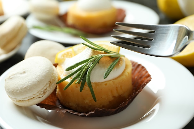 Concept of tasty breakfast with lemon cupcakes and macaroons