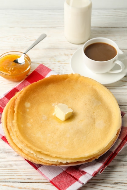 Concept of tasty breakfast with thin pancakes on white wooden table