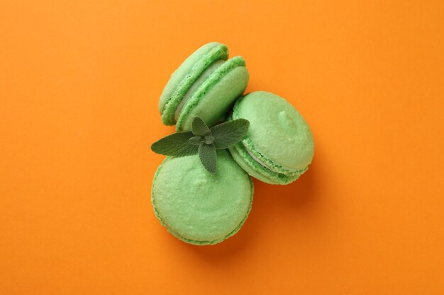 Concept of tasty dessert with macarons on orange background