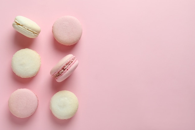 Concept of tasty dessert with macaroons on pink background