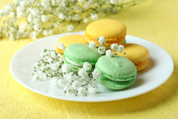 Concept of tasty dessert with macaroons on yellow background