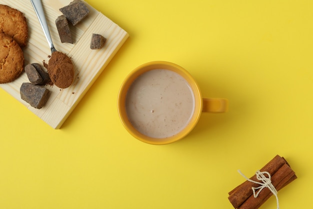 Concept of tasty drink with cocoa on yellow background