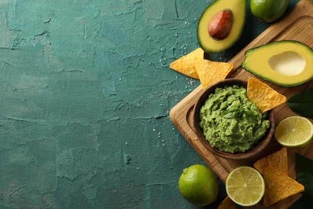 Концепция вкусной еды с миской гуакамоле на зеленом текстурированном фоне
