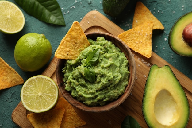 Concept of tasty eating with bowl of guacamole on green textured background