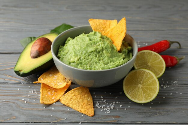 Concept of tasty eating with bowl of guacamole on wooden background