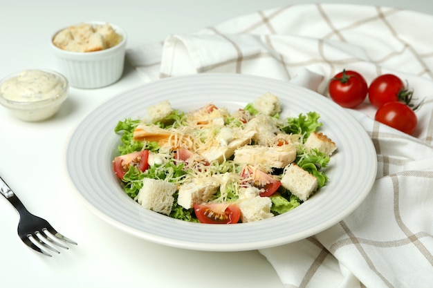 Concept of tasty eating with Caesar salad on white table