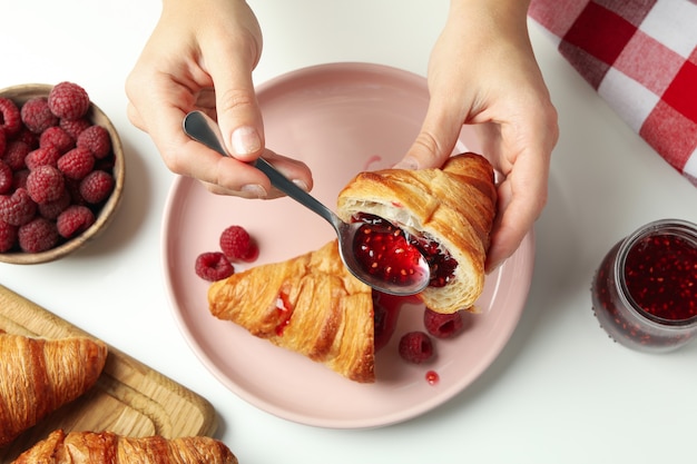 Concept of tasty eating with croissant with raspberry jam on white background