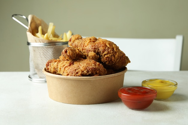 Concept of tasty eating with fried chicken on white textured table