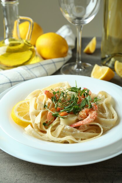 灰色の織り目加工のテーブルにエビのパスタとおいしい食事の概念