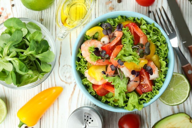 Concept of tasty eating with shrimp salad on white wooden table