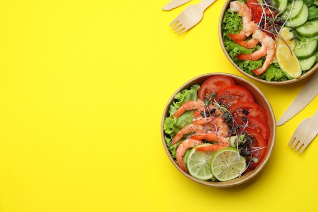 Concept of tasty eating with shrimp salads on yellow background