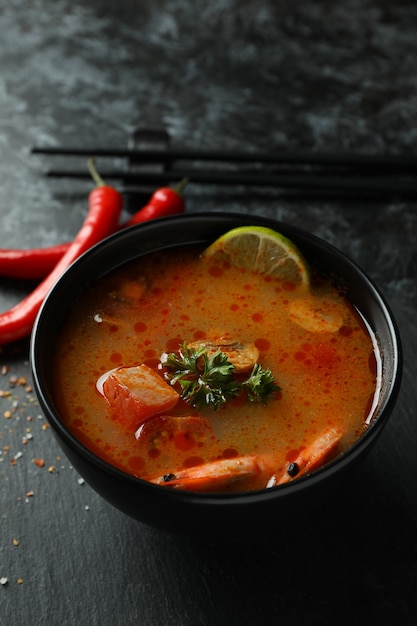 Photo concept of tasty eating with tom yum soup on black smokey background