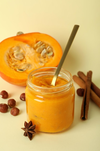 Concept of tasty food pumpkin jam and ingredients on beige background