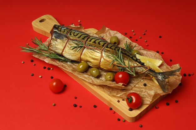 Concept of tasty food smoked mackerel on red background