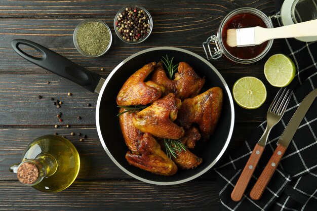 Concept of tasty food with baked chicken wings on wooden