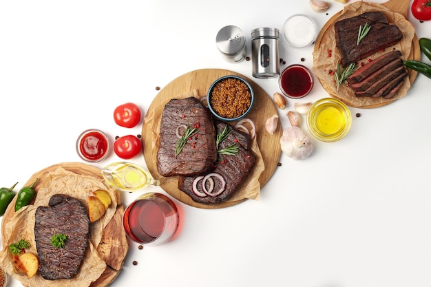 Concept of tasty food with beef steaks on white background