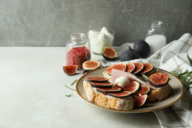 Photo concept of tasty food with bruschetta with fig on white textured table