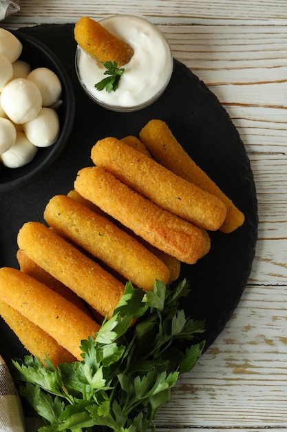 Concept of tasty food with cheese sticks on white wooden table