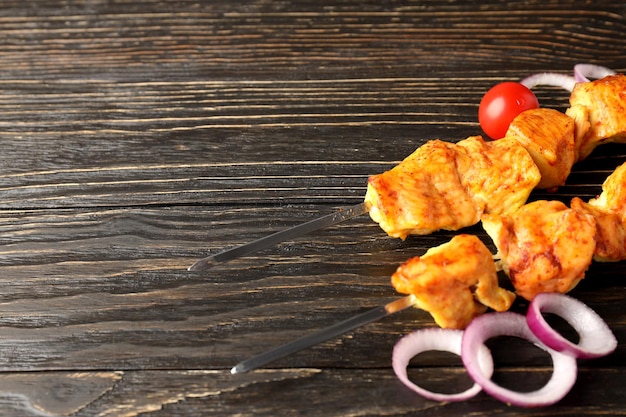 Concetto di cibo gustoso con spiedini di pollo su fondo di legno scuro