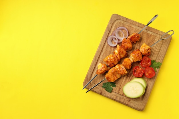 Concept of tasty food with chicken shashlik on yellow background