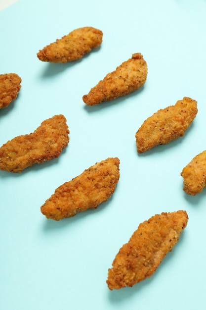 Concept of tasty food with chicken strips on blue
background