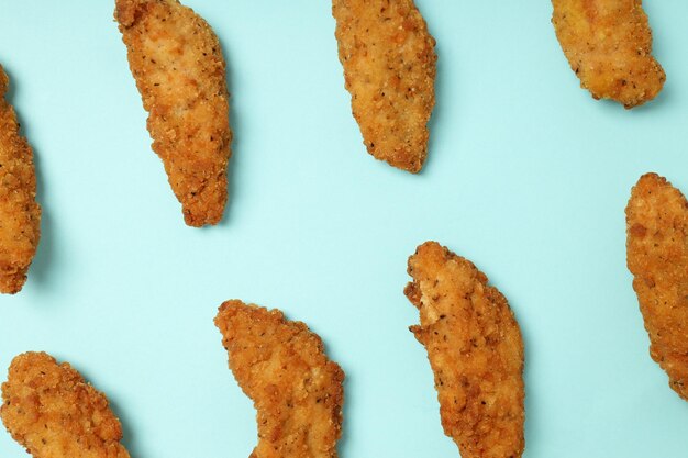 Concept of tasty food with chicken strips on blue\
background