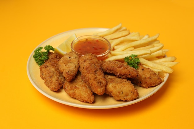 Concept of tasty food with chicken strips on orange\
background