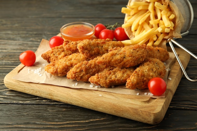 Concetto di cibo gustoso con strisce di pollo su tavola di legno