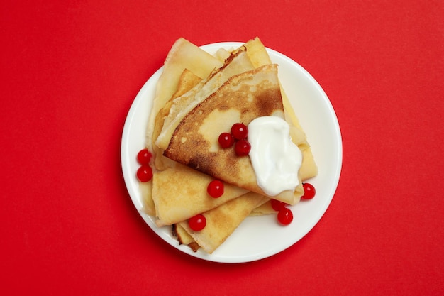 Concetto di cibo gustoso con crepes su sfondo rosso