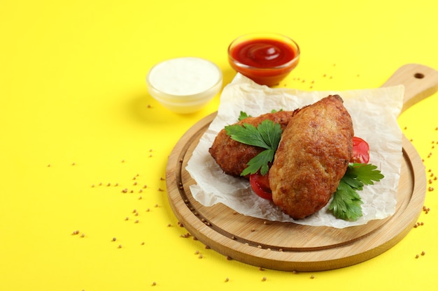 Concept of tasty food with cutlets on yellow background