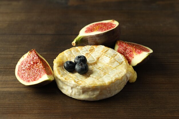 Concept of tasty food with grilled camembert on wooden background.